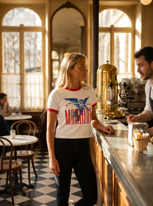 Woman in a cafe wearing a t-shirt with a graphic design, standing near a counter.