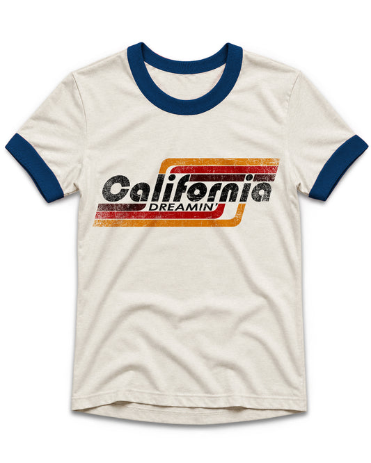 An off-white ringer t-shirt with navy blue collar and sleeve cuffs, featuring a distressed retro graphic on the chest that reads 'California DREAMIN'' in black text over orange and red stripes.
