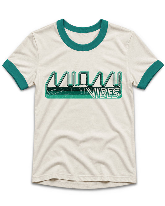 An off-white ringer t-shirt with teal trim on the collar and sleeve cuffs, featuring a distressed teal and white 'MIAMI VIBES' graphic across the chest.