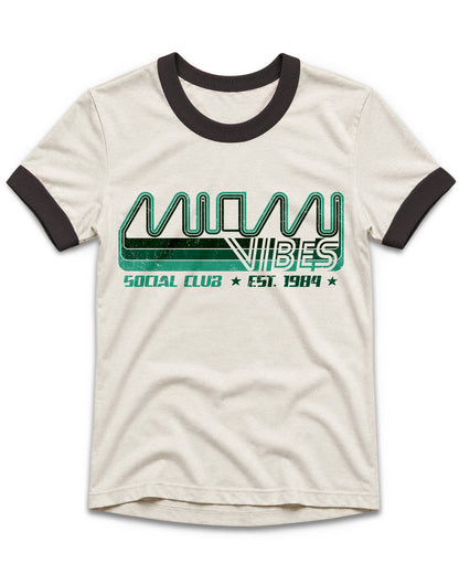 An off-white ringer t-shirt with black ribbed collar and sleeve cuffs, featuring a green and black graphic print on the front that reads 'MIAMI VIBES SOCIAL CLUB EST. 1984'.